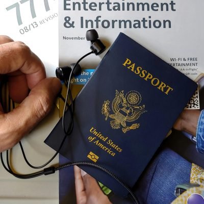 Close-up of US passport with inflight magazine and headphones on an airplane seat, ready for travel.